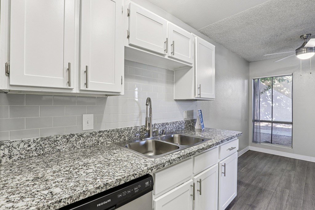 A kitchen with granite countertops and white cabinets.