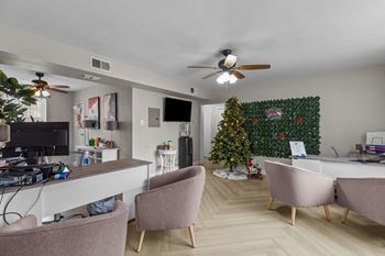 a living room with a christmas tree and a desk and chairs