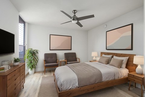 A bedroom with a large bed, a ceiling fan, and a painting on the wall.