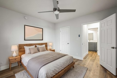 A bedroom with a bed, nightstands, and a ceiling fan.