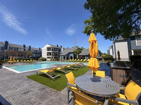 A pool area with yellow chairs and umbrellas.