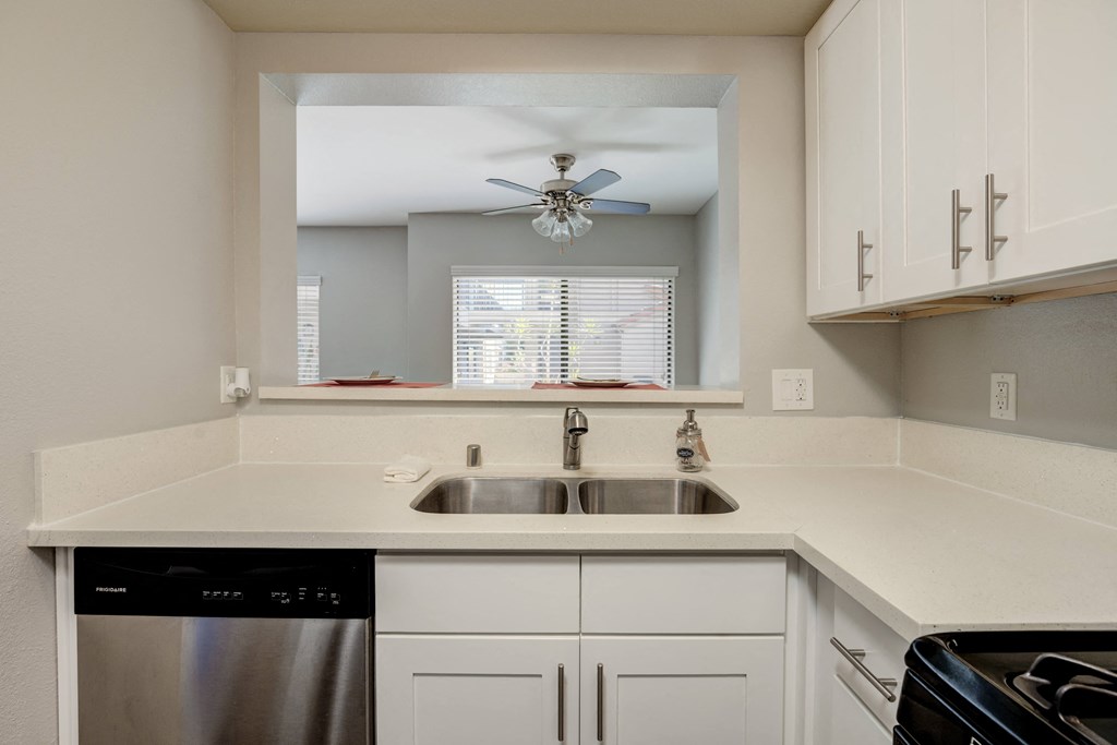 a kitchen with white cabinets and a sink and a ceiling fan