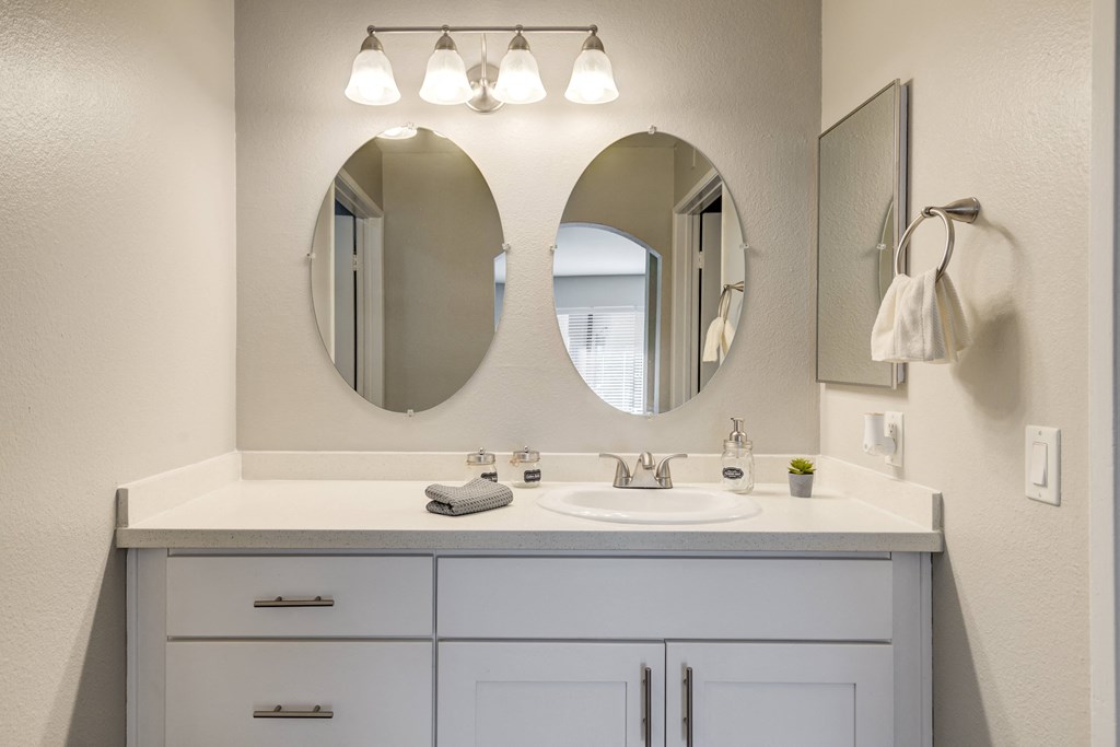 a white bathroom with two mirrors and a sink