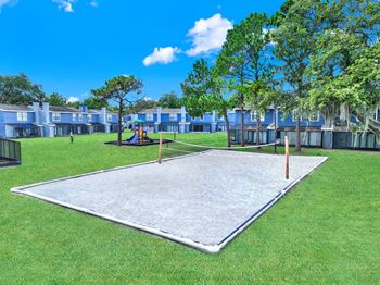 A playground with a slide and a seesaw in the middle of a grassy area.