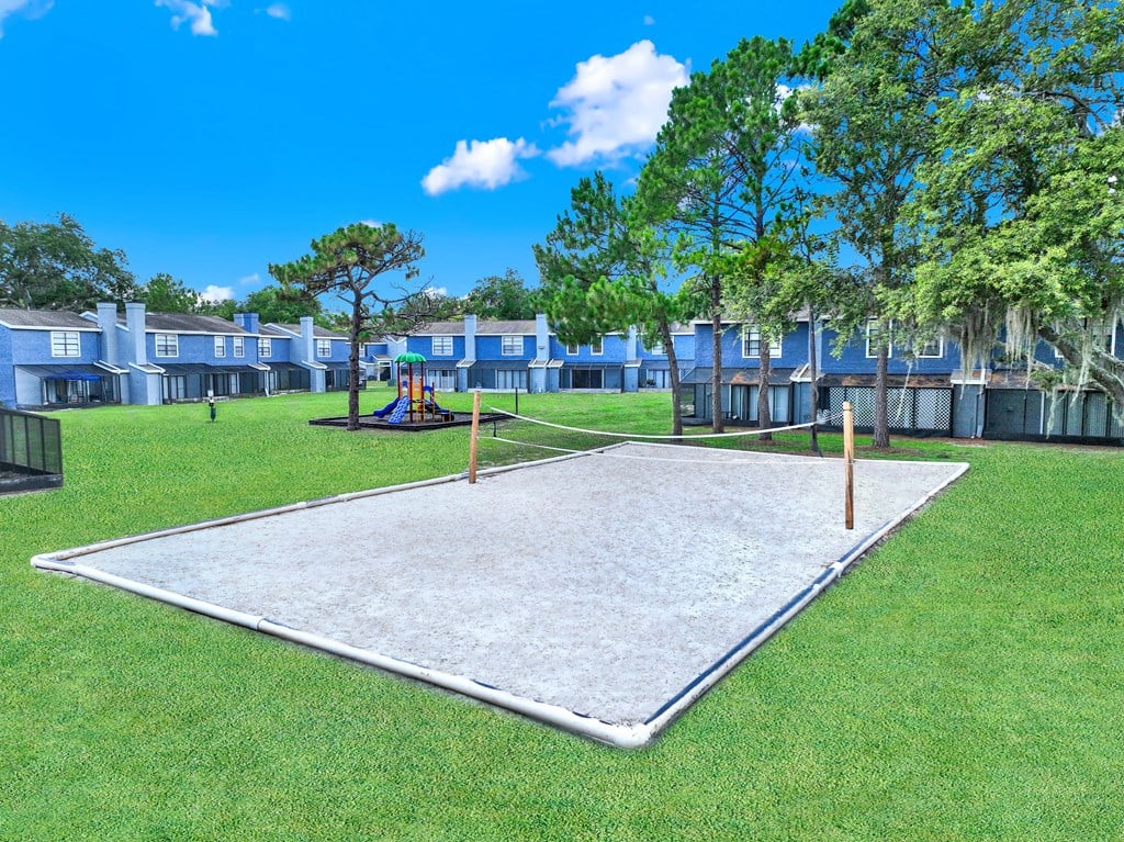 A playground with a slide and a seesaw in the middle of a grassy area.