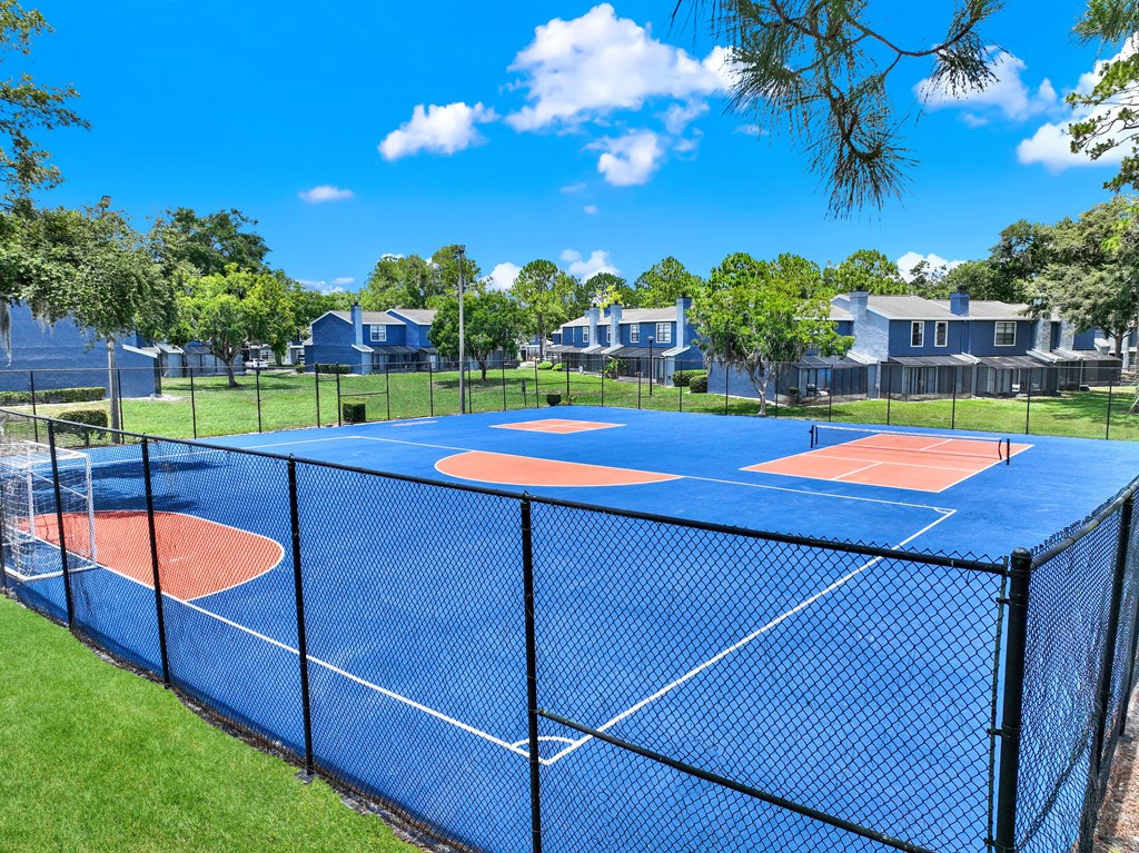 A blue tennis court surrounded by a black fence.