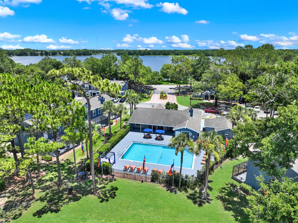A bird's eye view of a house with a swimming pool surrounded by trees.