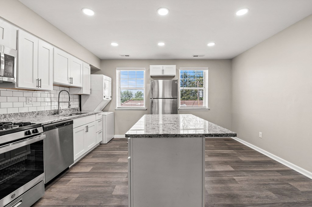 a kitchen with white cabinets and a large island with granite countertops at Hampton Gardens, Missouri, 63139