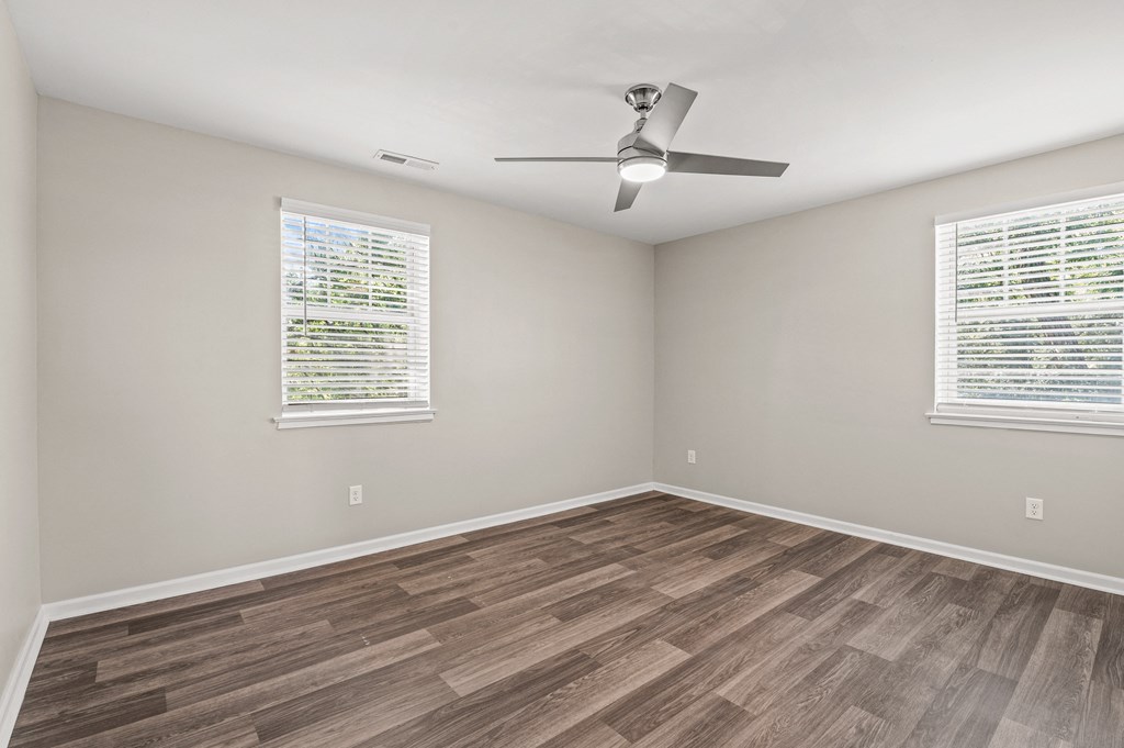 an empty room with a ceiling fan and two windows at Hampton Gardens, Saint Louis, MO, 63139