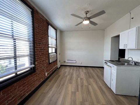 an empty apartment with a kitchen and a ceiling fan