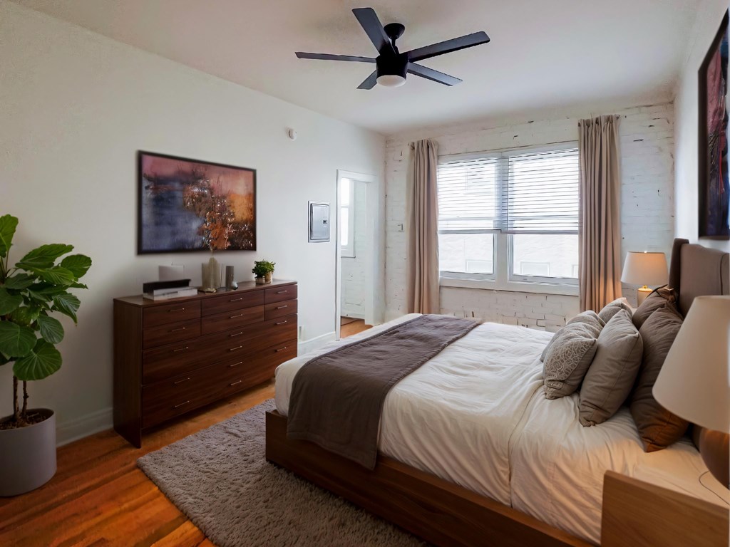 A bedroom with a bed, dresser, and ceiling fan at Kenmore Park Apartments, California