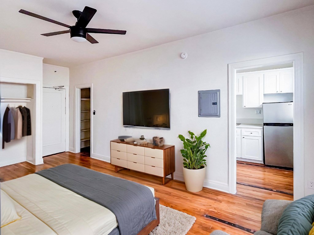 A bedroom with a bed, dresser, and a ceiling fan at Kenmore Park Apartments, Los Angeles, California