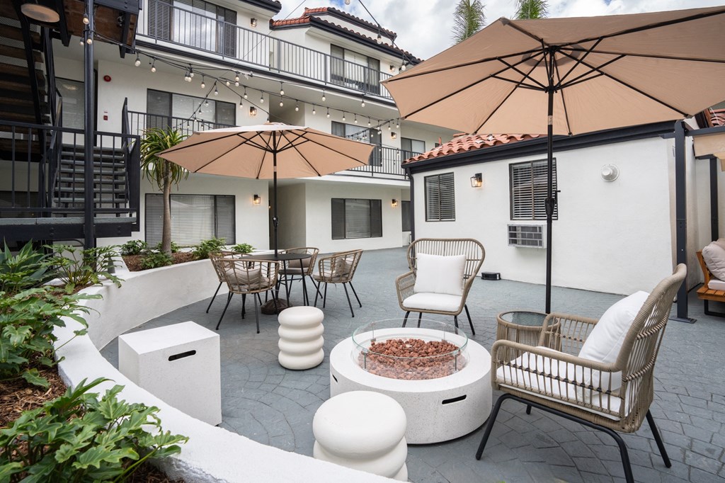 a patio with tables and chairs and umbrellas and a fire pit