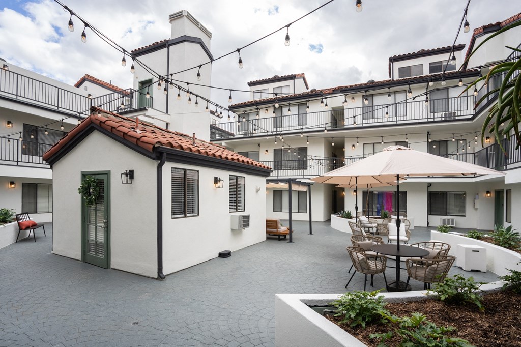 the courtyard of a white apartment building with tables and chairs