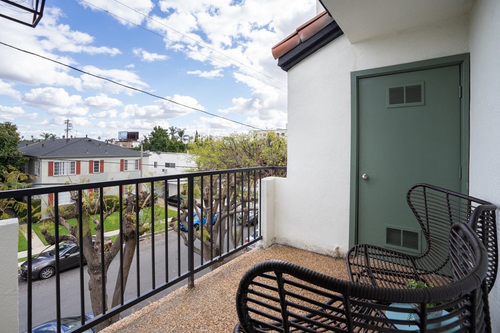 a balcony with a green door and two chairs on it