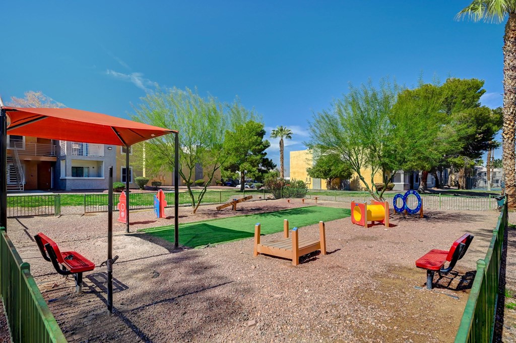 A playground with a red canopy and a green fence.