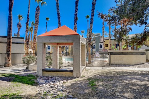 A gazebo with a red roof is surrounded by palm trees.