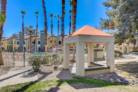 A gazebo-like structure sits in the middle of a courtyard with palm trees in the background.