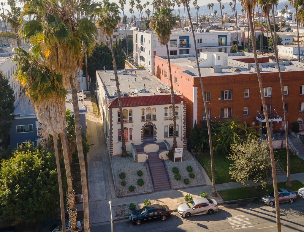 A building with a red roof is surrounded by palm trees at Hillstone Flats Apartments, Los Angeles, CA