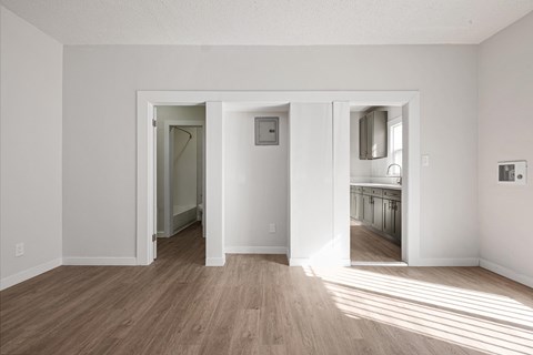 A room with white walls and wooden flooring with three open doors at Hillstone Flats Apartments, California
