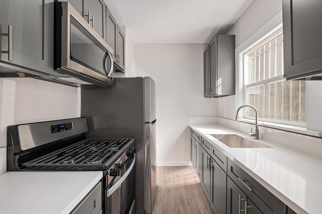 A modern kitchen with stainless steel appliances and wooden floors at Hillstone Flats Apartments, Los Angeles, CA, 90004