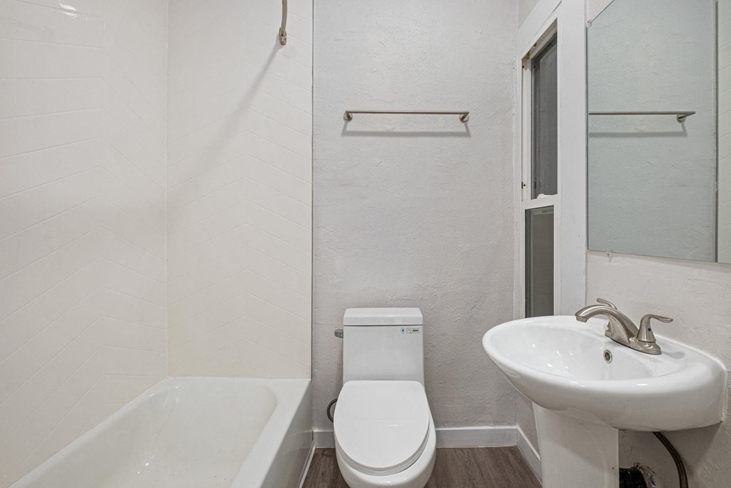 A white toilet sits next to a white sink in a small bathroom at Hillstone Flats Apartments, California 90004