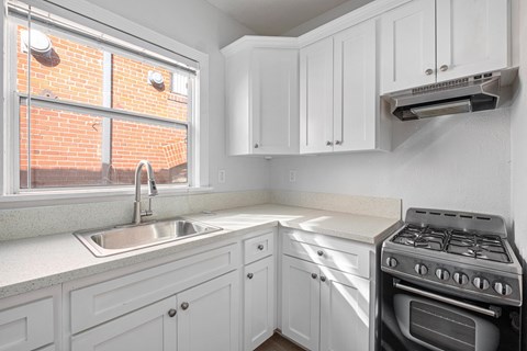A kitchen with white cabinets and a stove top oven at Hillstone Flats Apartments, Los Angeles, California