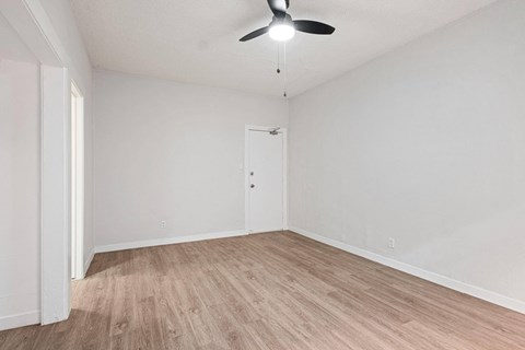 A room with a ceiling fan and light fixture, a door, and a wooden floor at Hillstone Flats Apartments, Los Angeles, CA, 90004