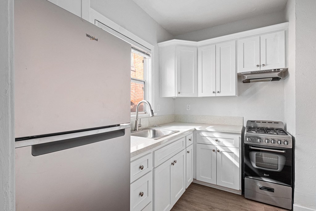A kitchen with a white fridge and a stove top oven at Hillstone Flats Apartments, Los Angeles