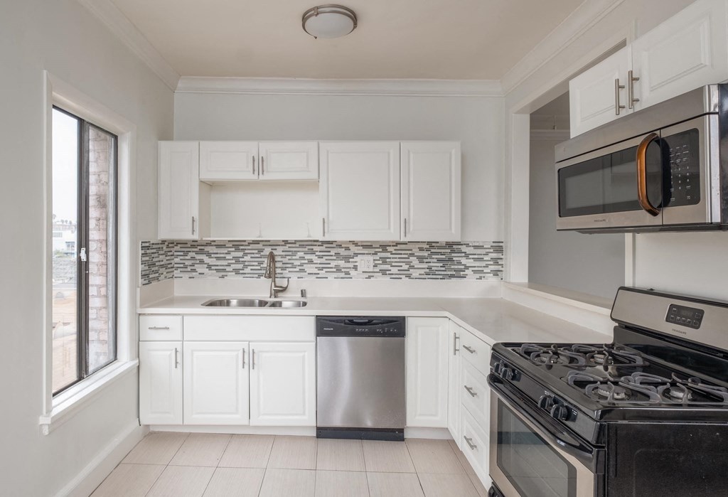 A kitchen with white cabinets and a black stove top oven. A kitchen with white cabinets and a black stove top oven at Mariposa Willows Apartments, Los Angeles, CA