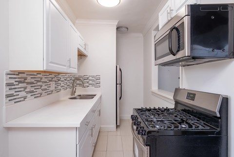 A kitchen with a black stove and white cabinets at Mariposa Willows Apartments, Los Angeles, California