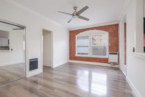 A room with a ceiling fan and a brick wall at Mariposa Willows Apartments, Los Angeles, 90004