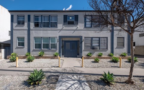 A grey building with a black door and windows with white frames.