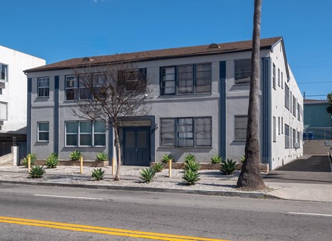 A grey building with a blue door and windows.