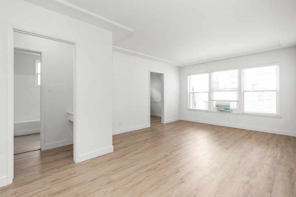 A white room with wooden floors and a window.at Normandie Grove, Los Angeles, CA 