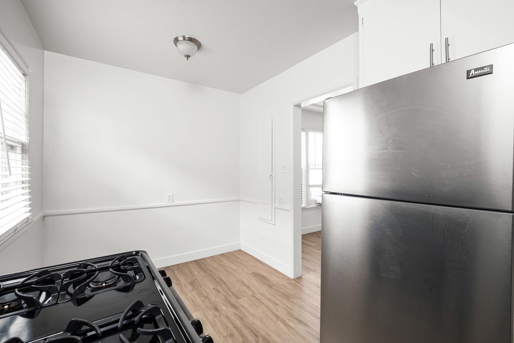 A modern kitchen with a stainless steel refrigerator and a black gas stove.at Normandie Grove, Los Angeles, CA 90004 