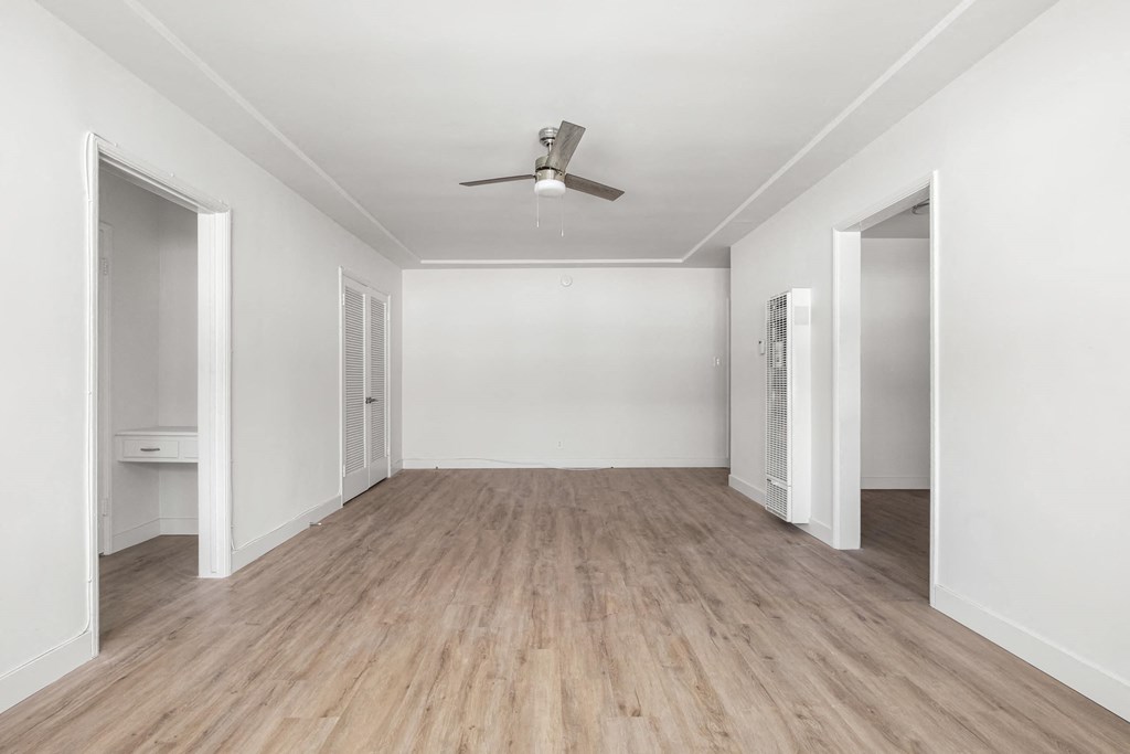 A room with a ceiling fan and light, and a wooden floor.at Normandie Grove, Los Angeles California 