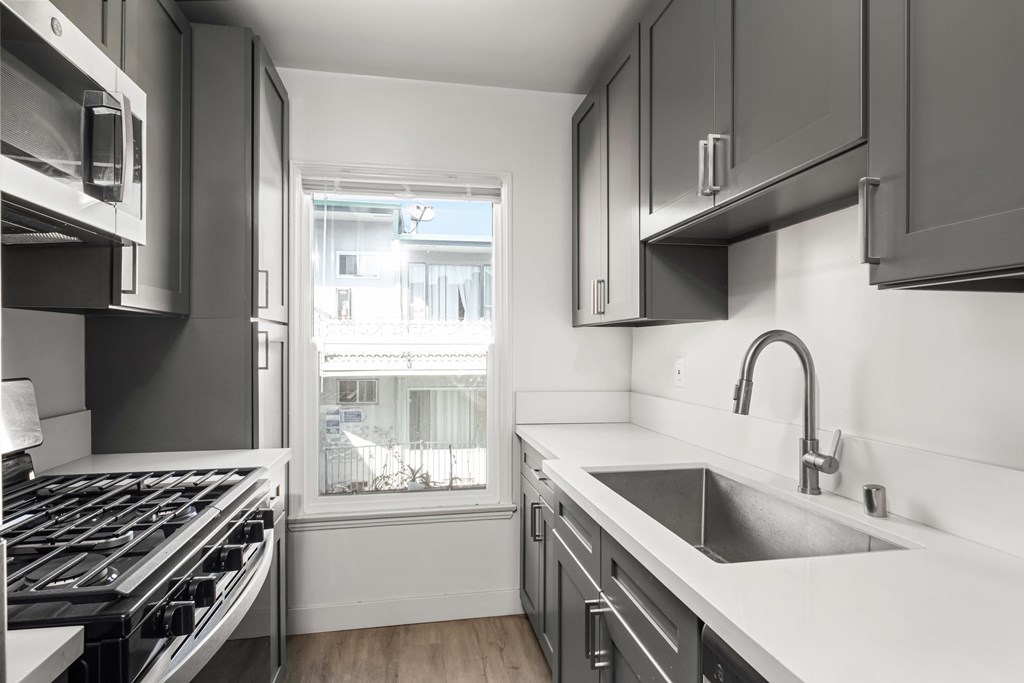 A modern kitchen with a stove top oven and a sink.