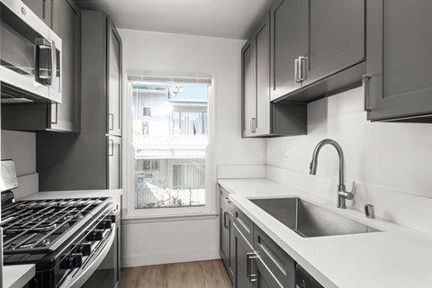 A modern kitchen with a stove top oven and a sink.