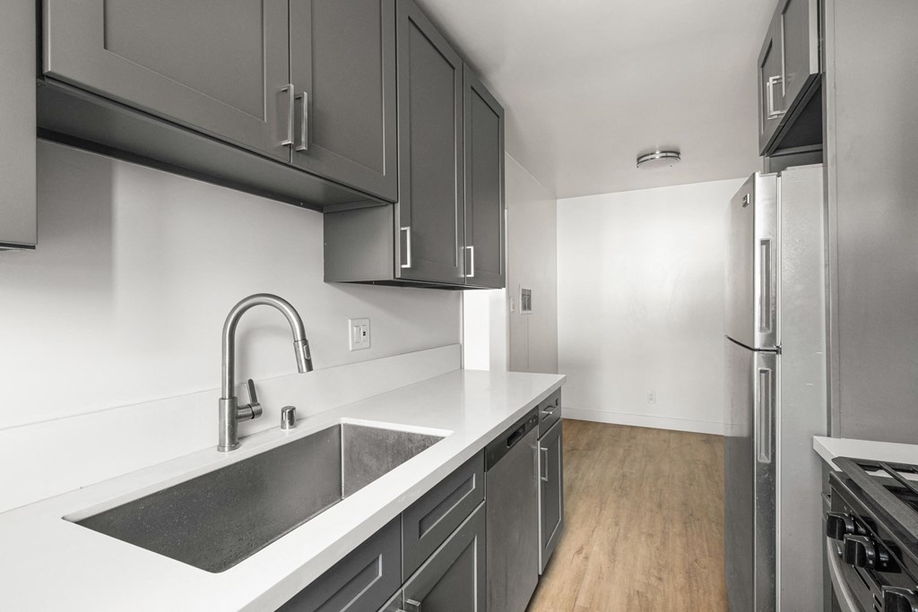 A modern kitchen with a stainless steel sink and refrigerator.at Normandie Grove, California, 90004
