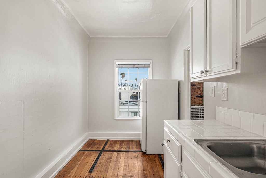 A kitchen with white cabinets and a window overlooking a cityscape. A kitchen with white cabinets and a window overlooking a cityscape at Normandie Summit Apartments, California 90004