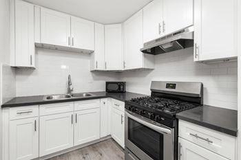 A kitchen with white cabinets and black countertops.at Palms at Menlo, Los Angeles, CA 