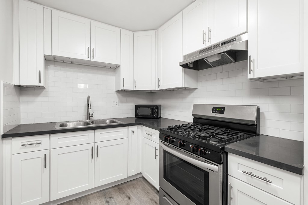 A kitchen with white cabinets and black countertops.at Palms at Menlo, Los Angeles California 