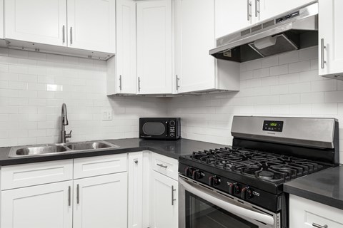 A modern kitchen with white cabinets and a black stove top.