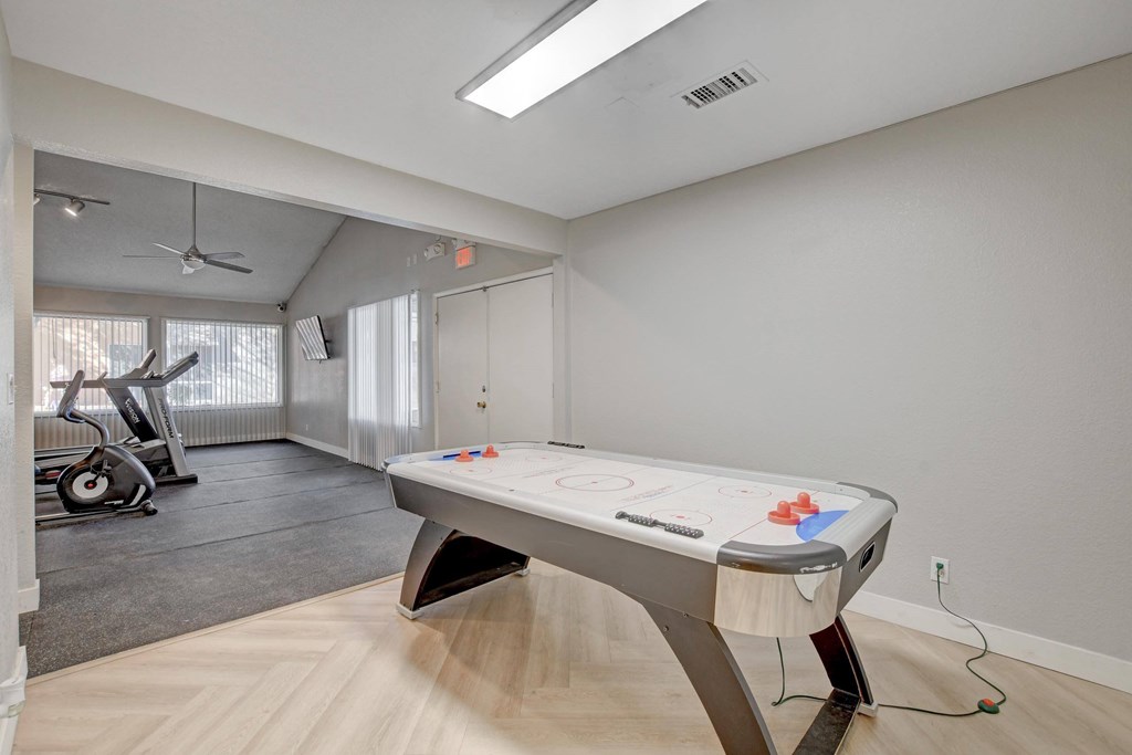 A pool table in a room with a fan and exercise equipment.
