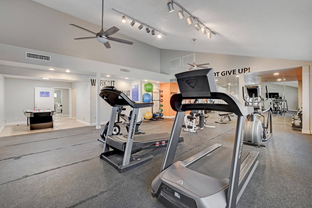 A gym with a variety of equipment including treadmills and weights.