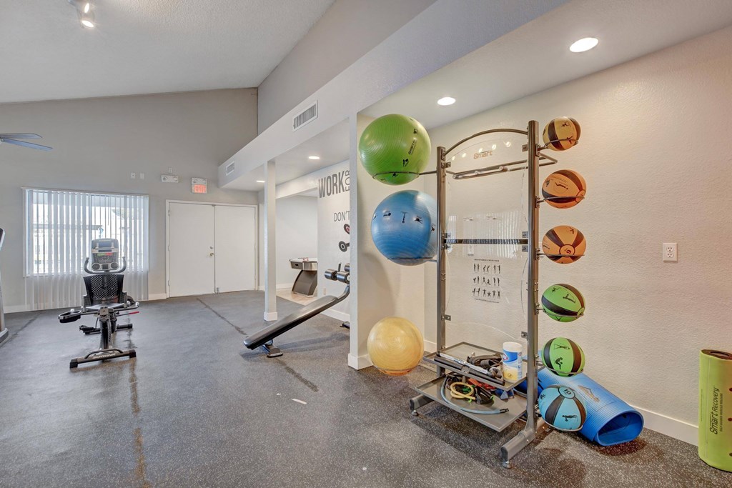 A room with a workout station and exercise balls.