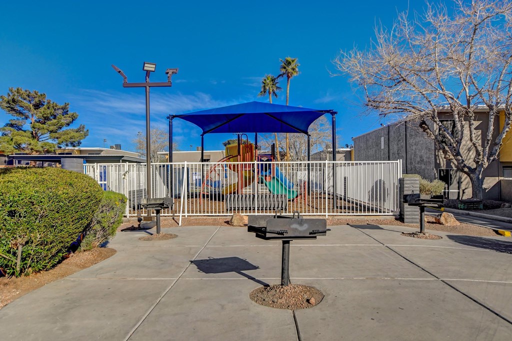 A playground with a blue canopy and a swing set.
