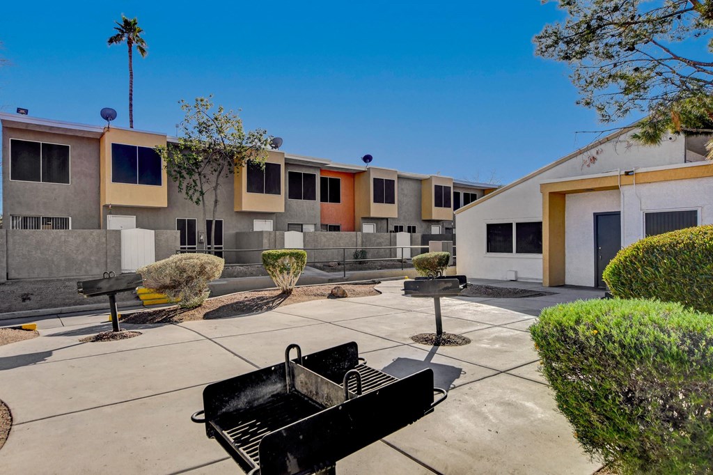 A black grill is in the middle of a concrete patio.