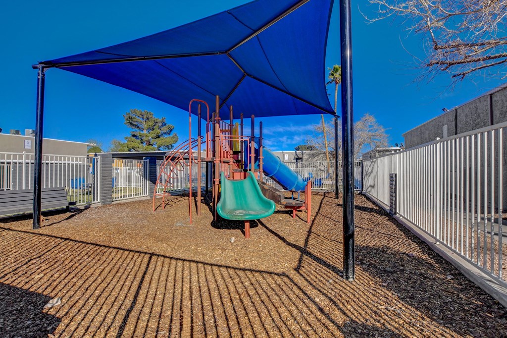 A playground with a blue canopy and a green slide.
